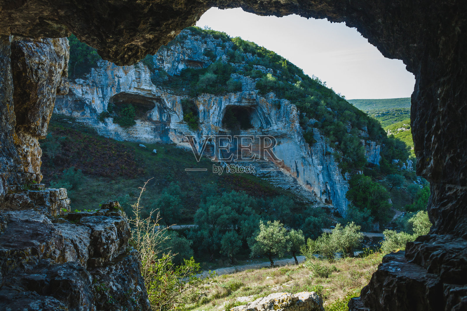 一处戏剧性的石灰岩悬崖,嵌有自然洞穴,可能是葡萄牙卡斯米洛地区的一部分。风化的岩石形成了浅灰色和棕色的混合色调。照片摄影图片