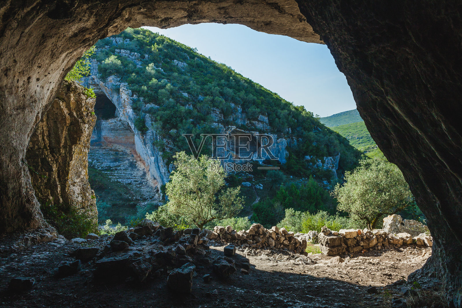 一处戏剧性的石灰岩悬崖,嵌有自然洞穴,可能是葡萄牙卡斯米洛地区的一部分。风化的岩石形成了浅灰色和棕色的混合色调。照片摄影图片