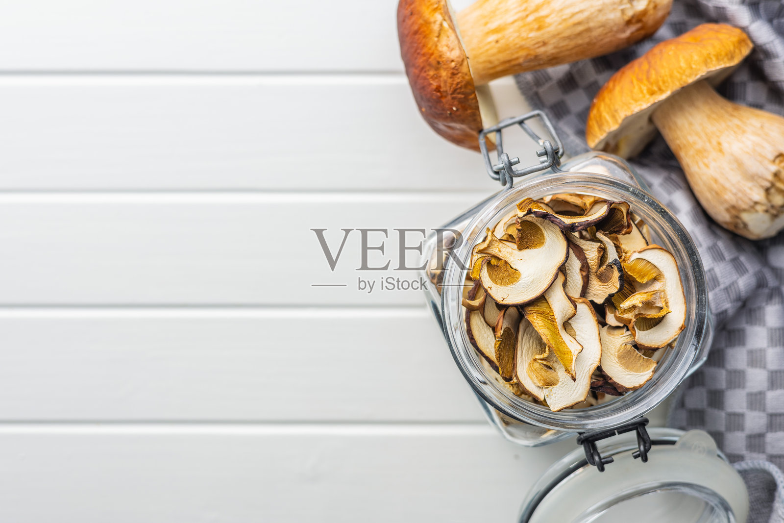 干香菇。白色桌子上的切片牛肝菌罐。照片摄影图片