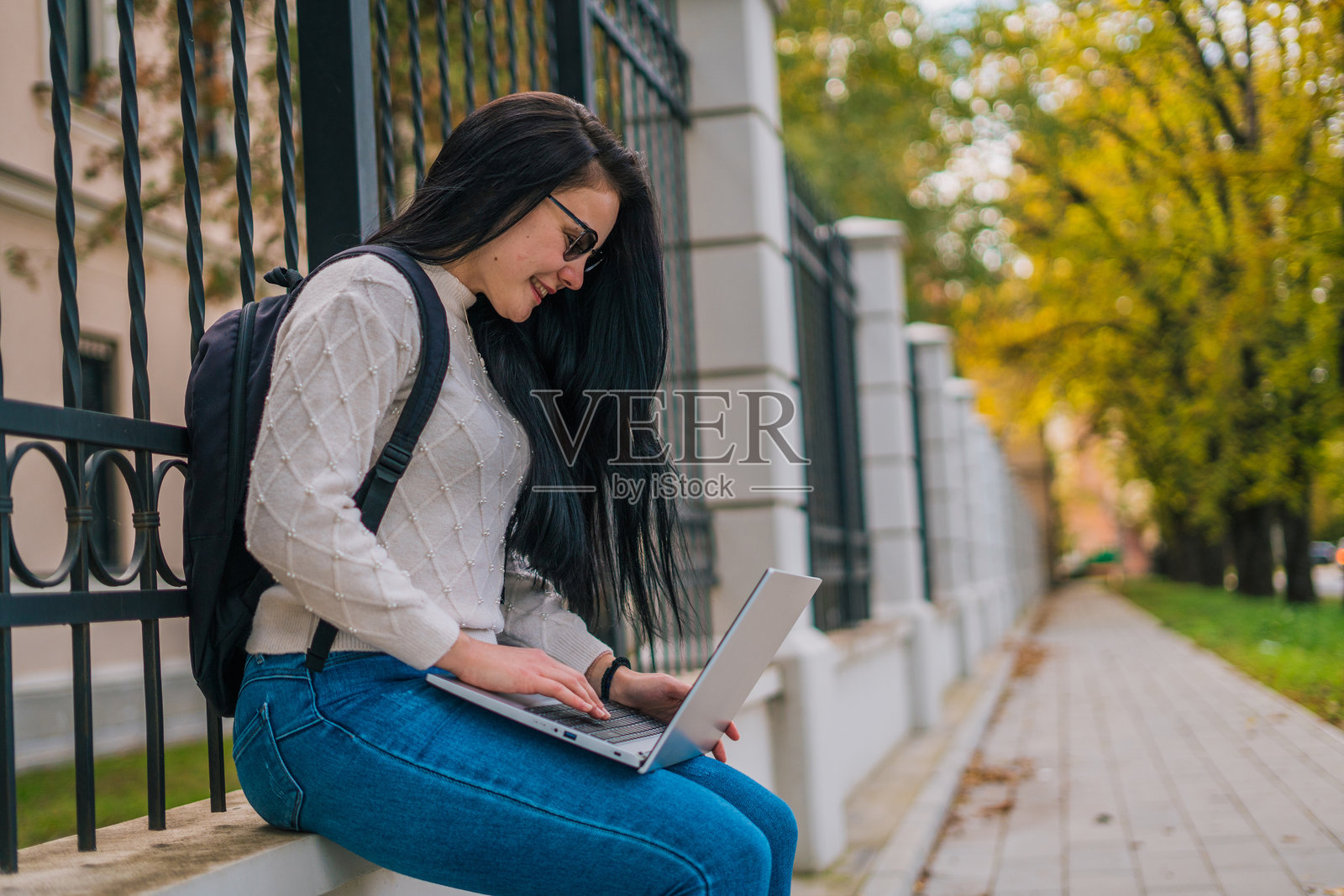 一名女学生坐在教职员工面前,背着书包,面前放着笔记本电脑。照片摄影图片
