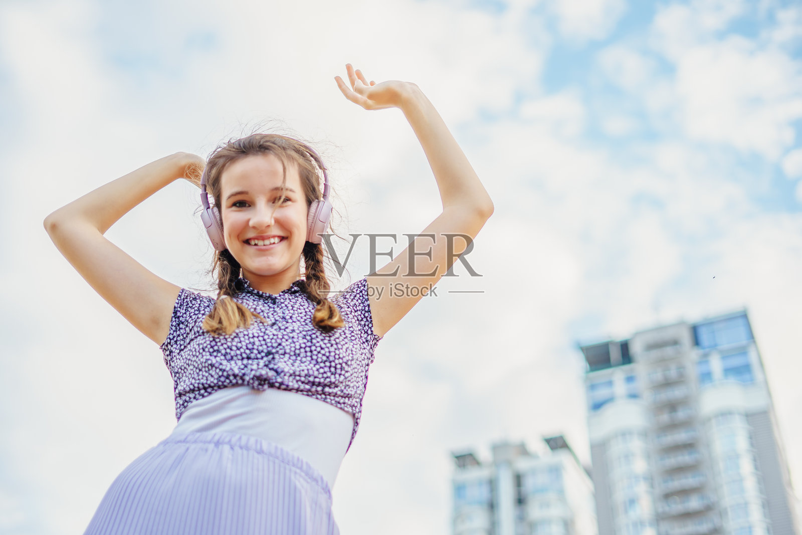 可爱快乐的女孩在夏季城市街道上听音乐跳舞照片摄影图片