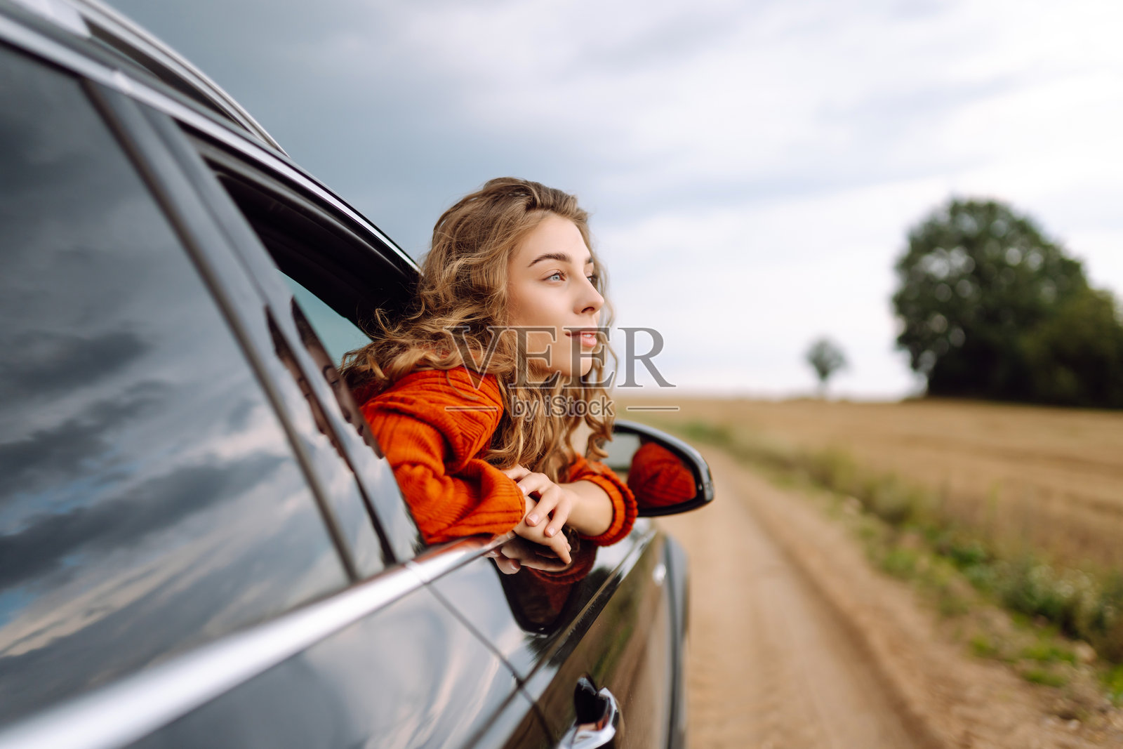 快乐的女人在车窗外休息并享受旅行。照片摄影图片