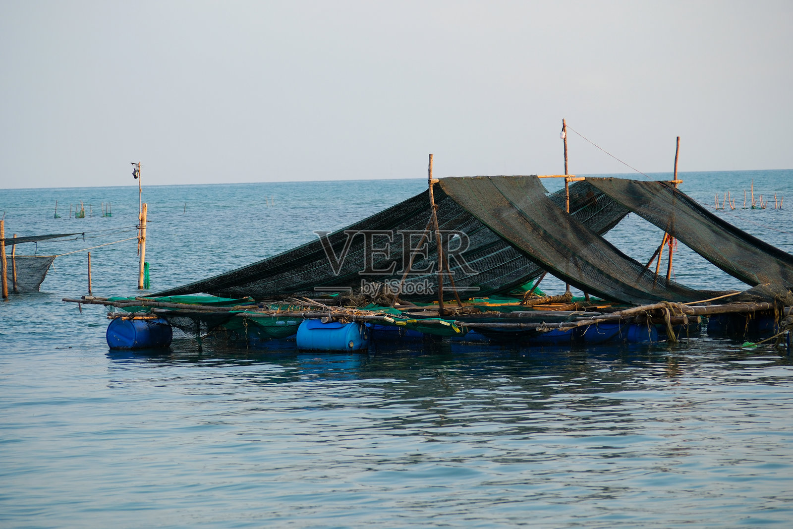 美丽的水面上,越南富国岛的印度洋渔村,鱼类养殖,木桥和房屋映衬着非凡的自然风光。照片摄影图片