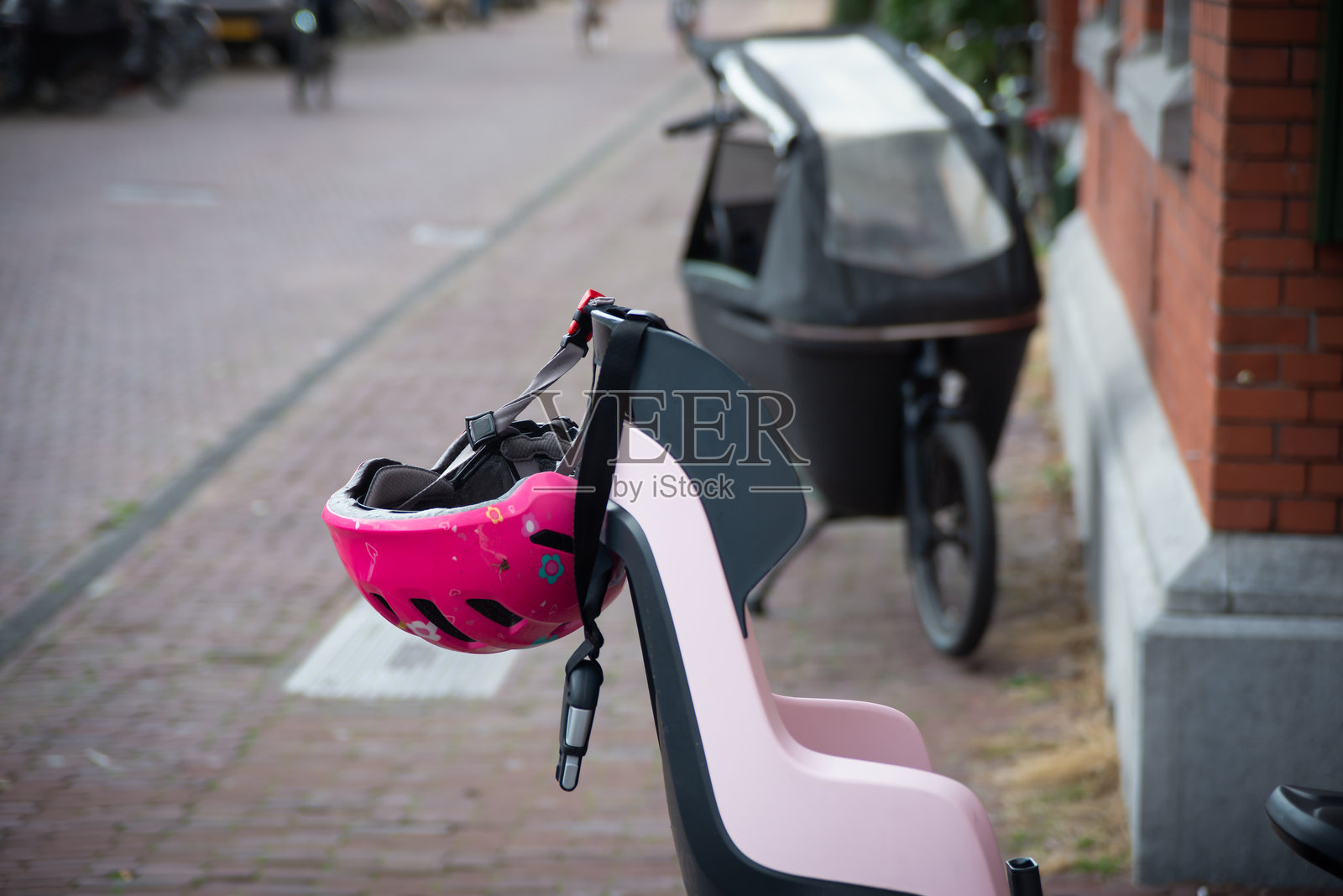 粉色安全头盔放在婴儿自行车座椅上。照片摄影图片