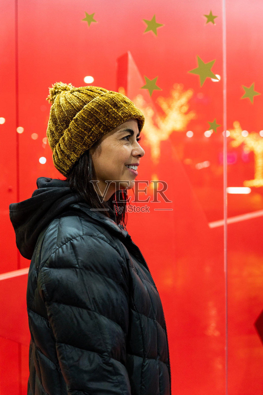 拉丁裔女性走过装饰着美丽圣诞灯饰的商店橱窗照片摄影图片