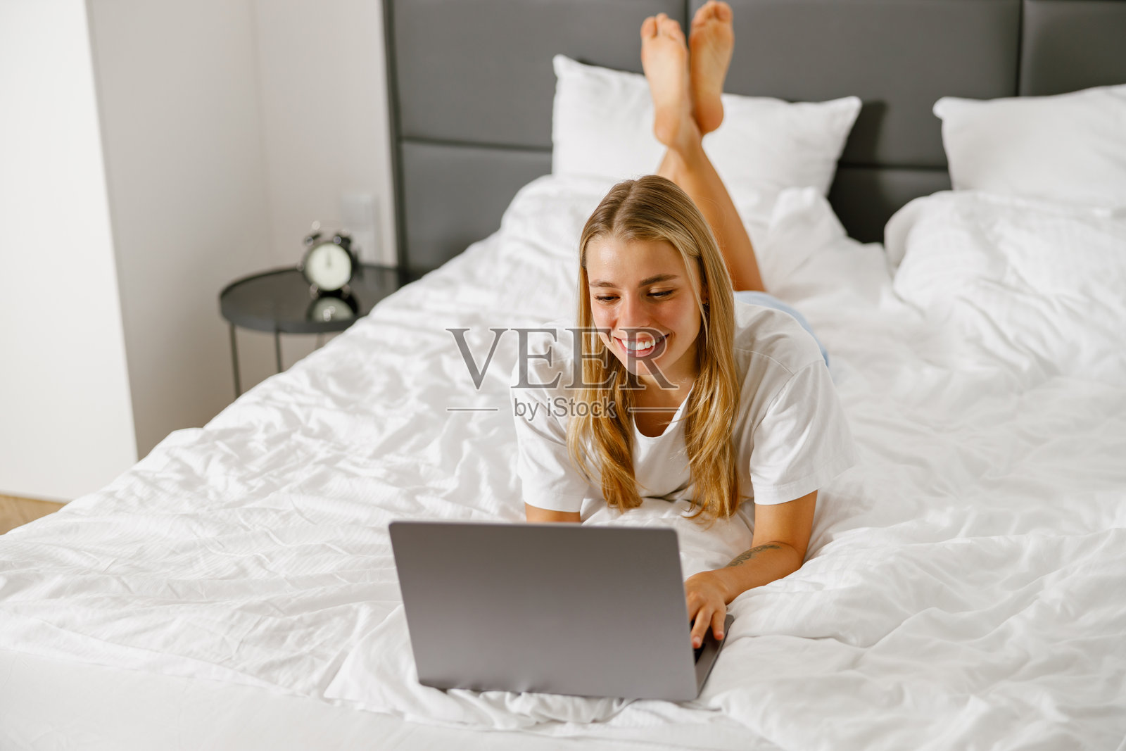 一位放松的年轻女性舒适地坐在床上使用笔记本电脑工作照片摄影图片