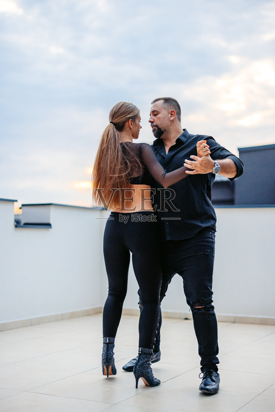中年男子与年轻女子在建筑物屋顶跳拉丁风格舞蹈照片摄影图片