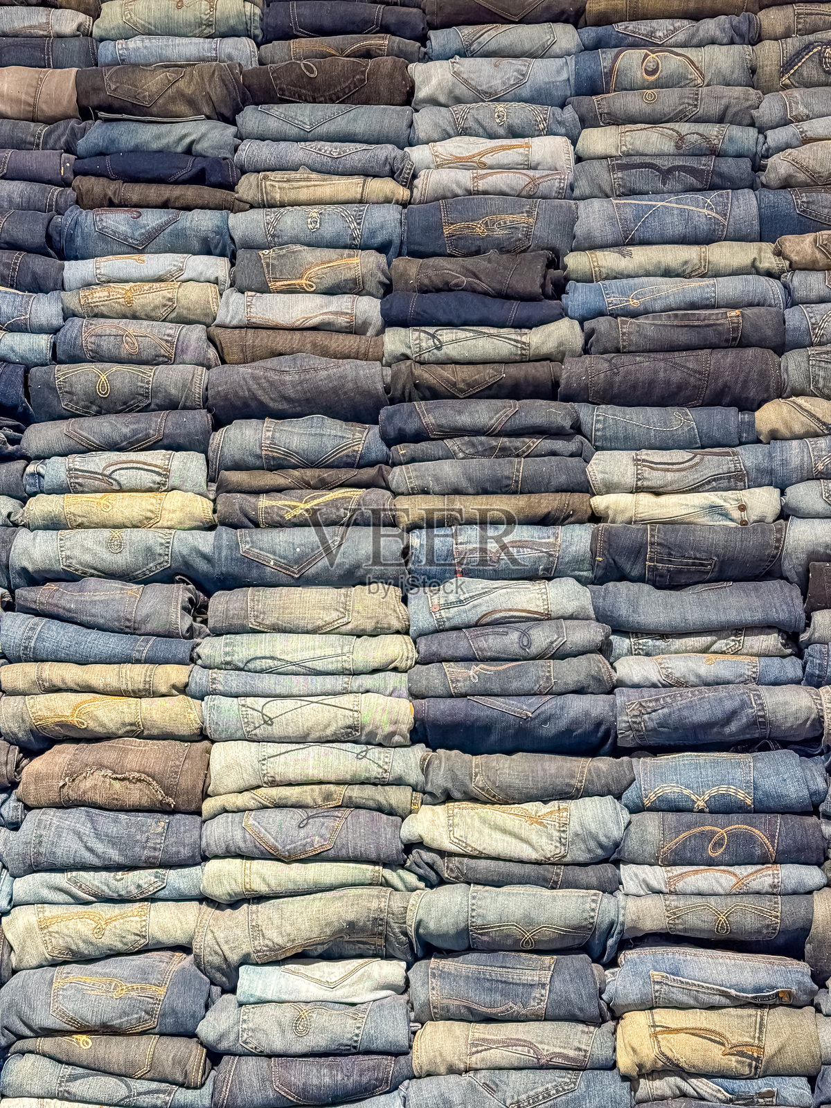 叠放的蓝色牛仔裤,呈现出丰富的纹理牛仔布图案照片摄影图片