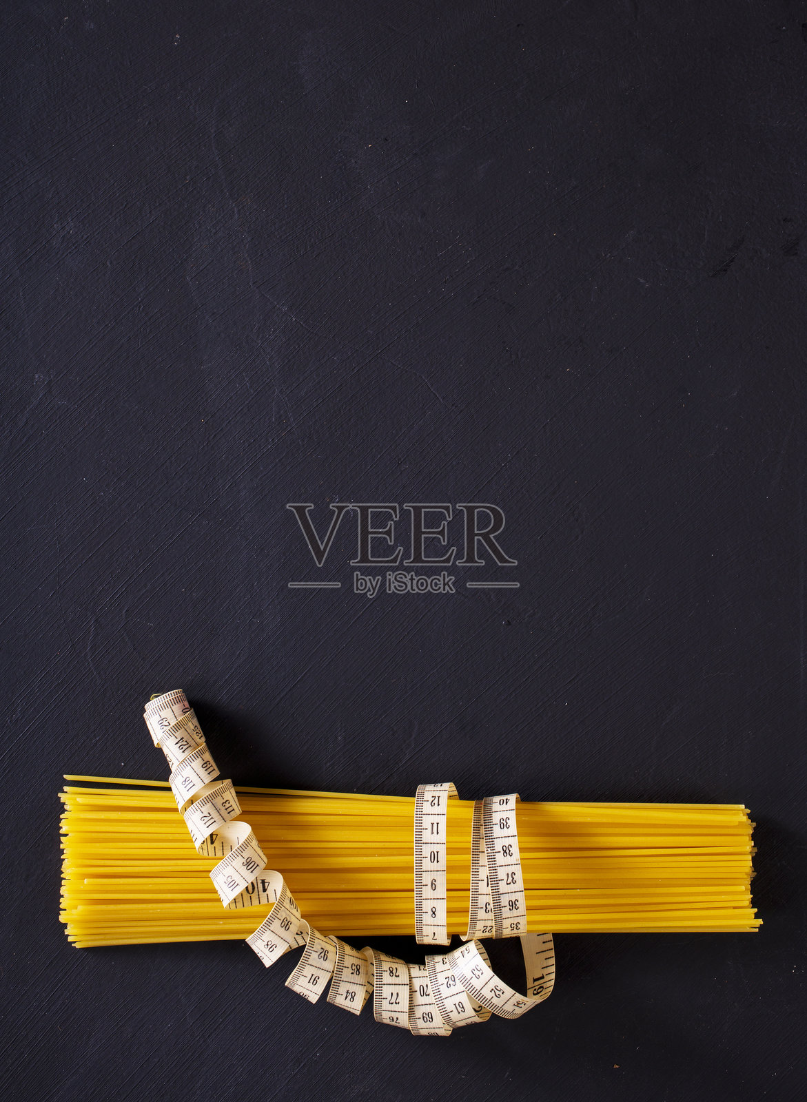 黑色背景上的意大利面。特写意大利面的纹理,体现了长条生食材和意大利美食的概念。照片摄影图片