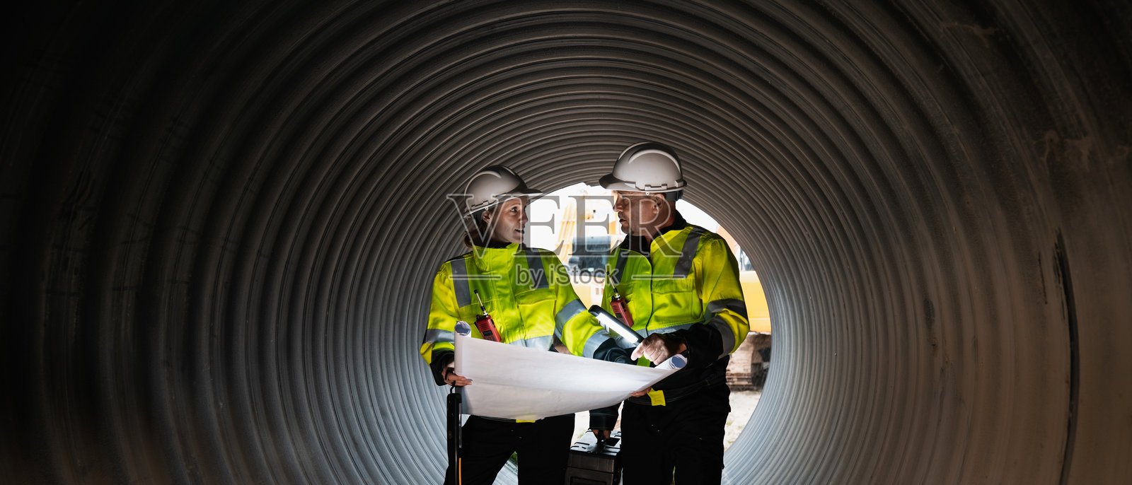 工程师在大型钢管内工作。工人在工业设施中建设用于运输石油、天然气和燃料的管道。照片摄影图片