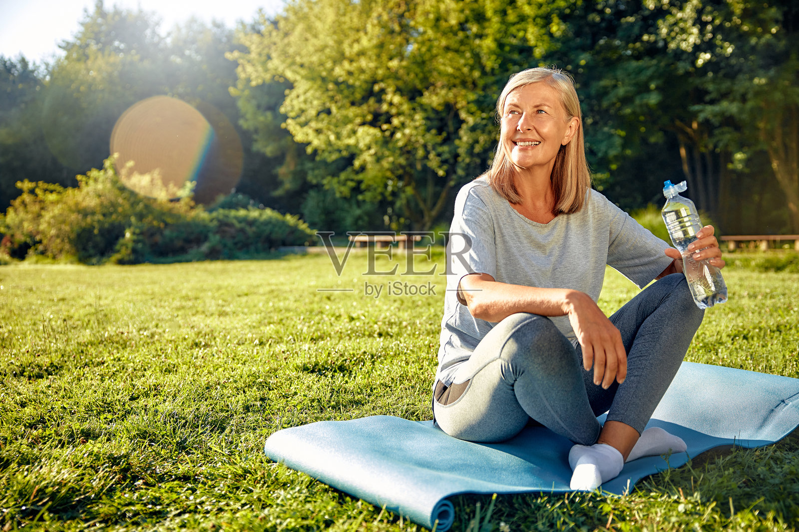 一位活跃的老年女性在大自然中享受她的健康之旅,同时携带着水瓶。照片摄影图片