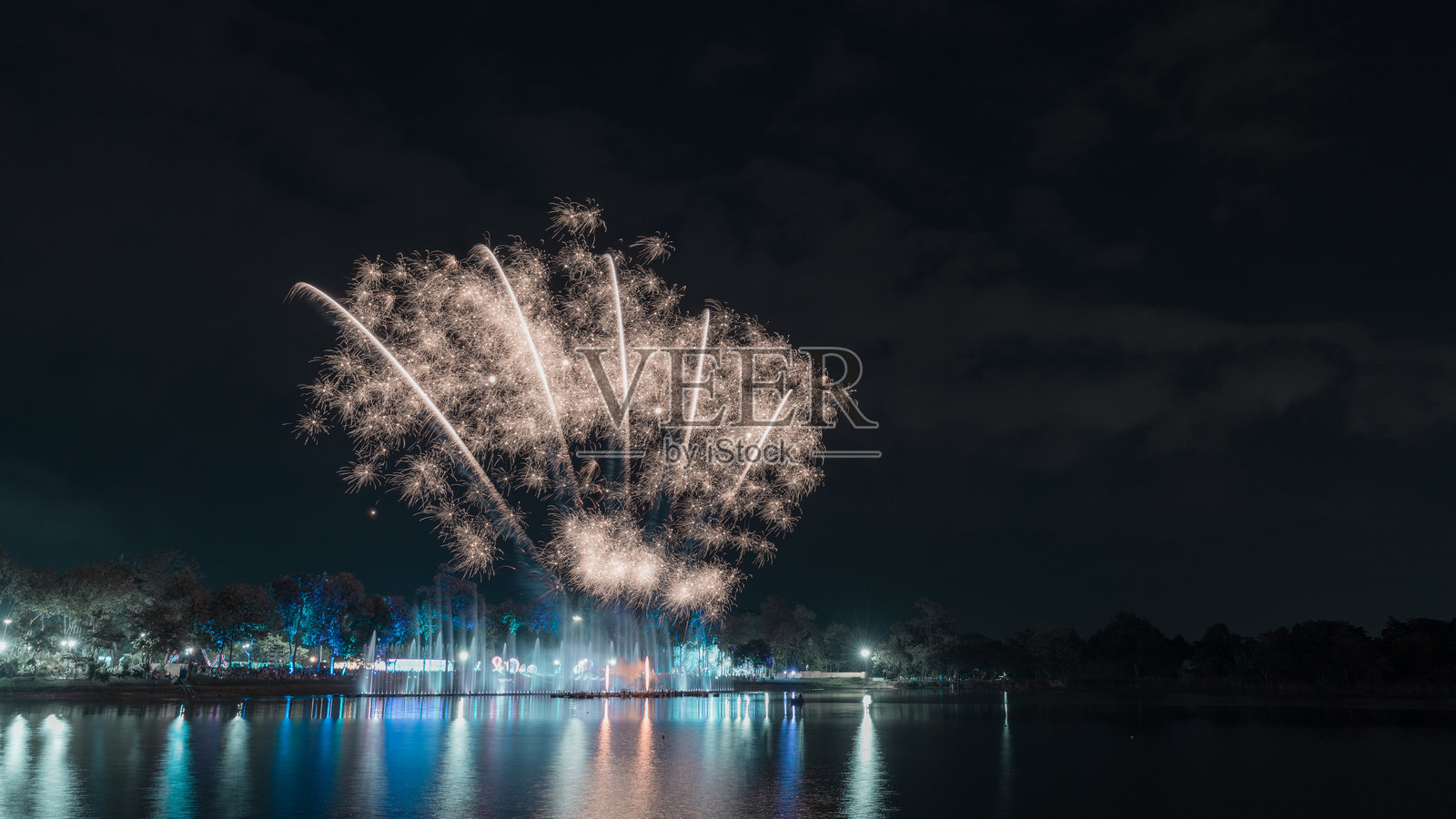 新年夜空中绚丽的烟花表演,水面上映出美丽的灯光和倒影。照片摄影图片