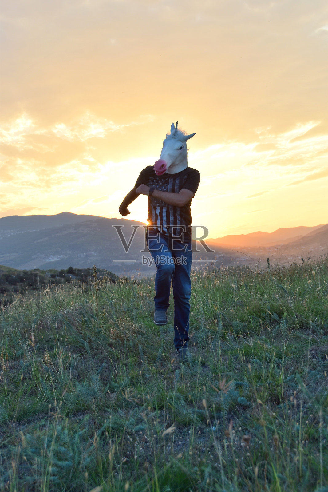 穿着马 costume 的男子在橙色天空下的田野上奔跑照片摄影图片