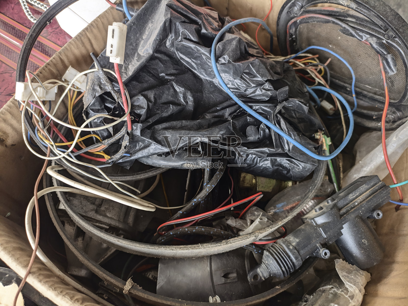 一堆旧电缆放在一个脏兮兮的纸箱里。小型未使用电缆。照片摄影图片