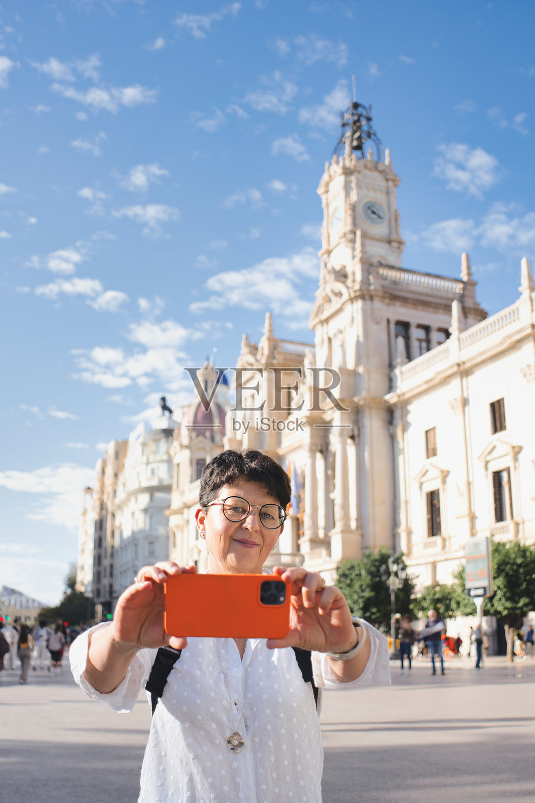 一位老年游客在阳光明媚的日子里拍摄西班牙瓦伦西亚市政厅的照片照片摄影图片