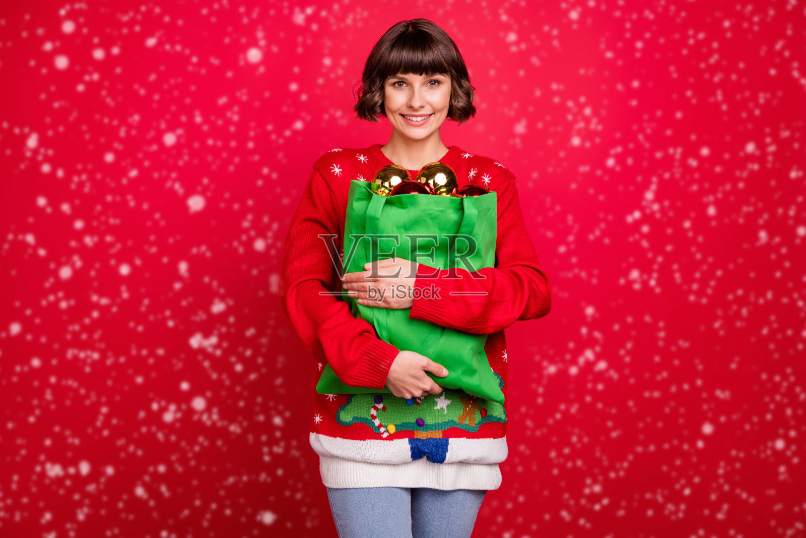 吸引人的快乐女孩手抱节日玩具,背景为红色。照片摄影图片