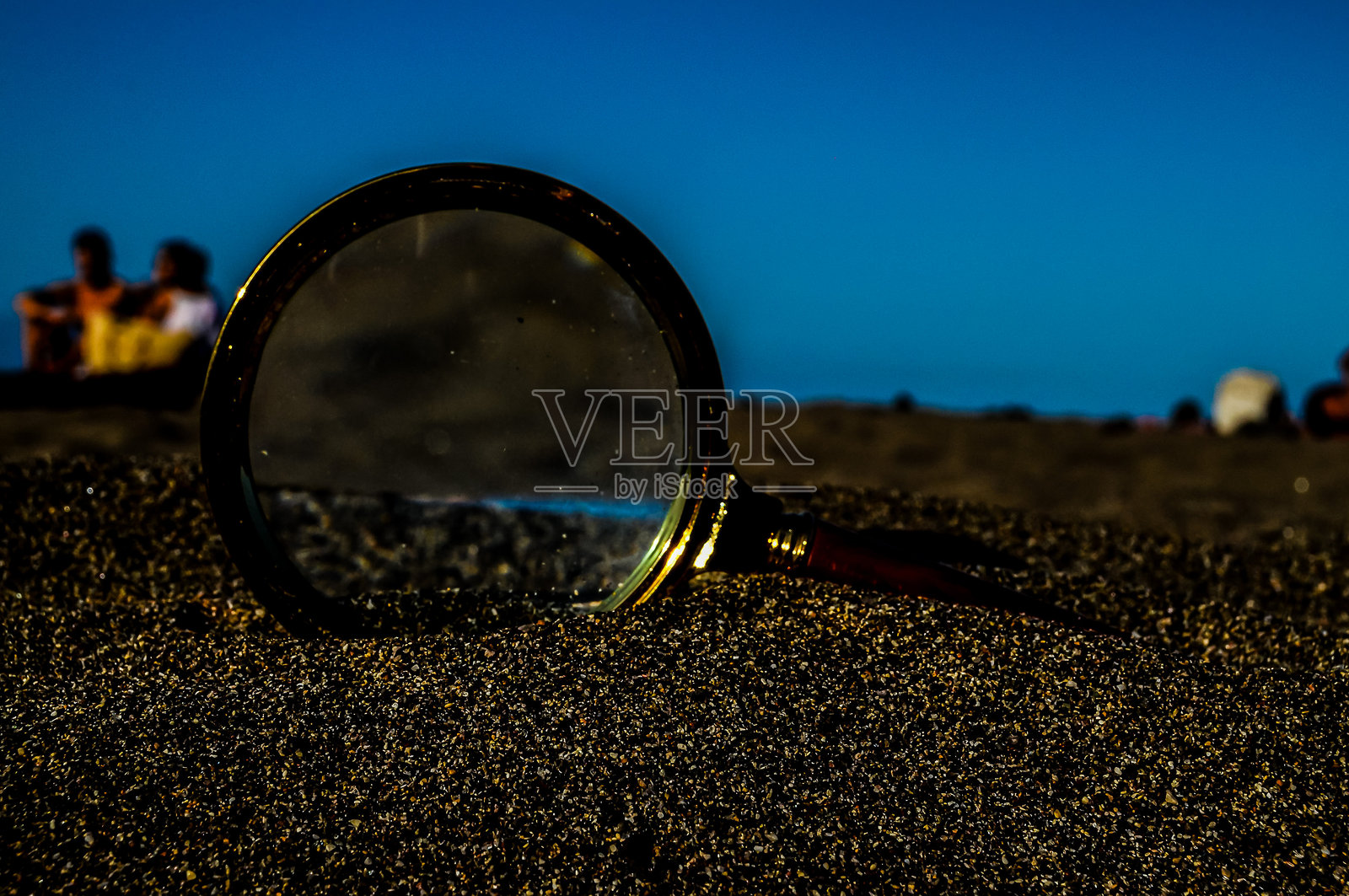 放大镜放在沙子上照片摄影图片