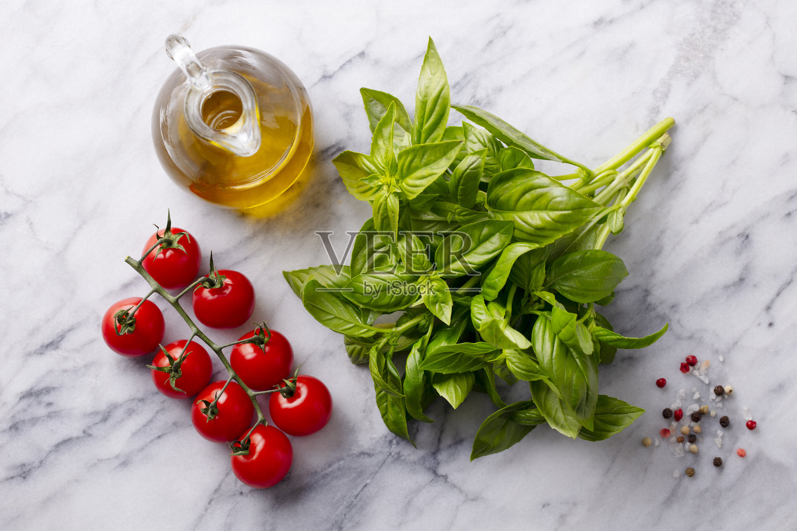 新鲜罗勒、樱桃番茄、橄榄油和香料在大理石桌面上。俯视图。照片摄影图片