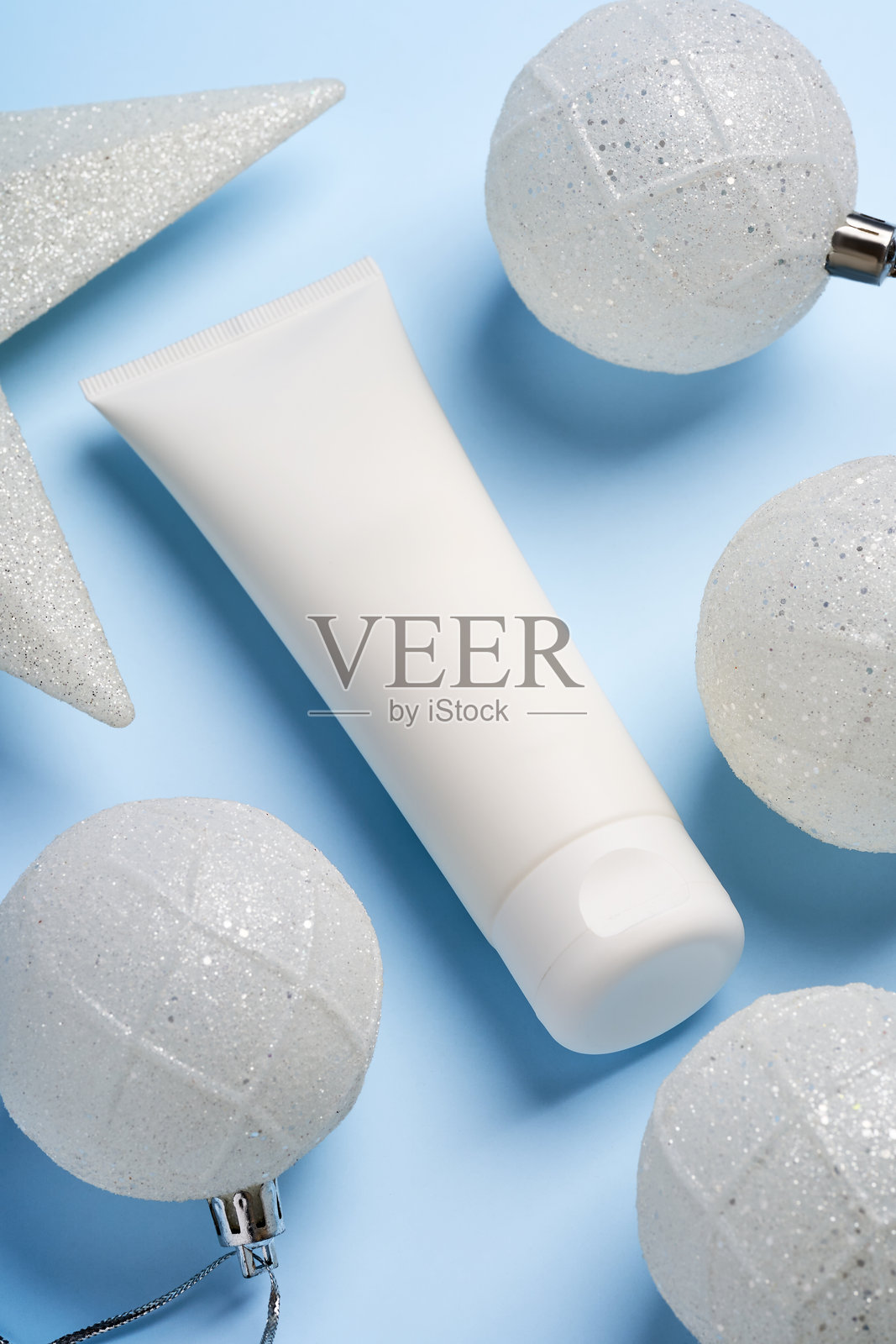 白色无品牌塑料管,装有面霜或面膜,背景为节日蓝色新年假日。适合作为节日美容护理礼物的展示。照片摄影图片