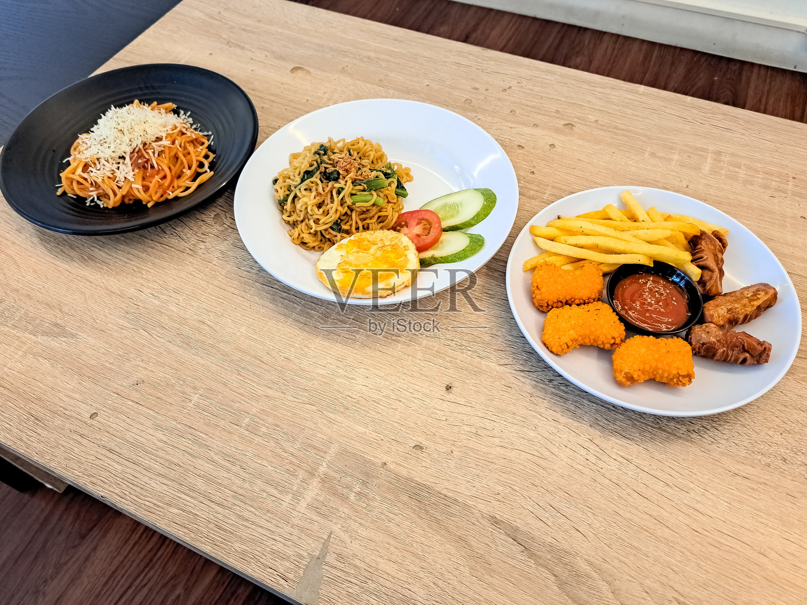 小吃拼盘,包括薯条、炸香肠和鸡块、炒蛋米粉或炒面以及意大利肉酱面。菜单。照片摄影图片