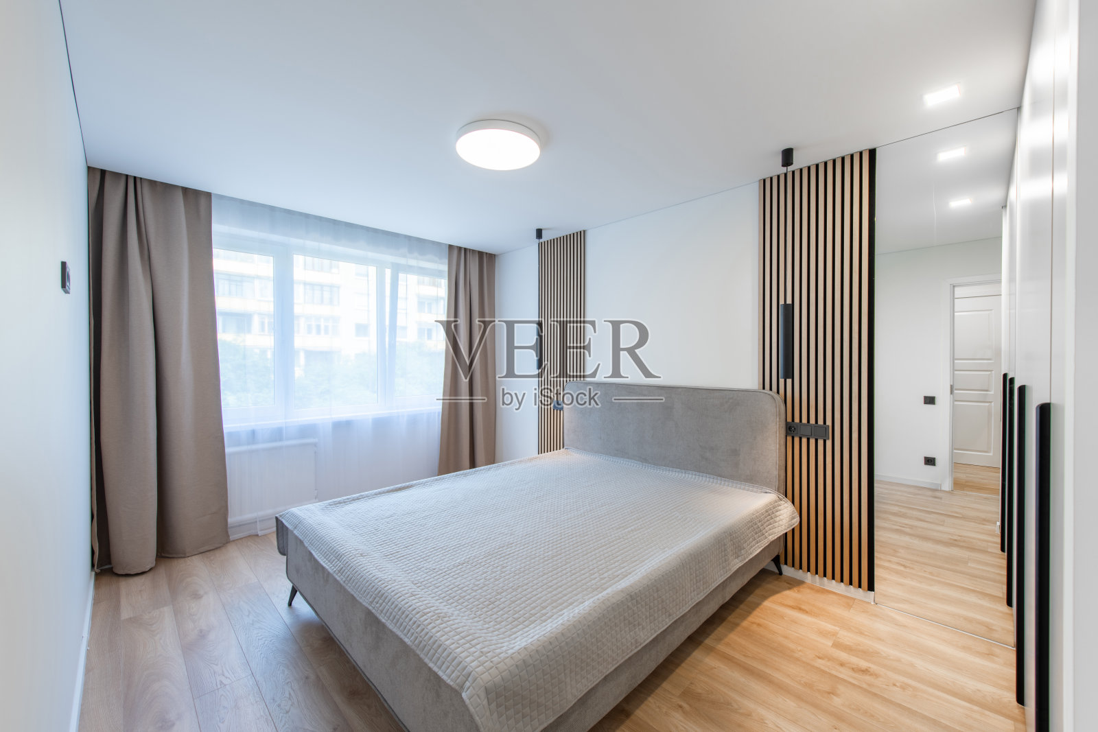 宽角度的家庭卧室内部。背景中有一张特大号双人床和衣柜。白色墙壁。家庭住宅。窗户和窗帘。照片摄影图片