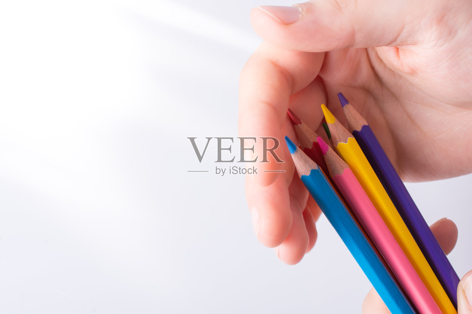 手握彩色铅笔,背景为白色照片摄影图片