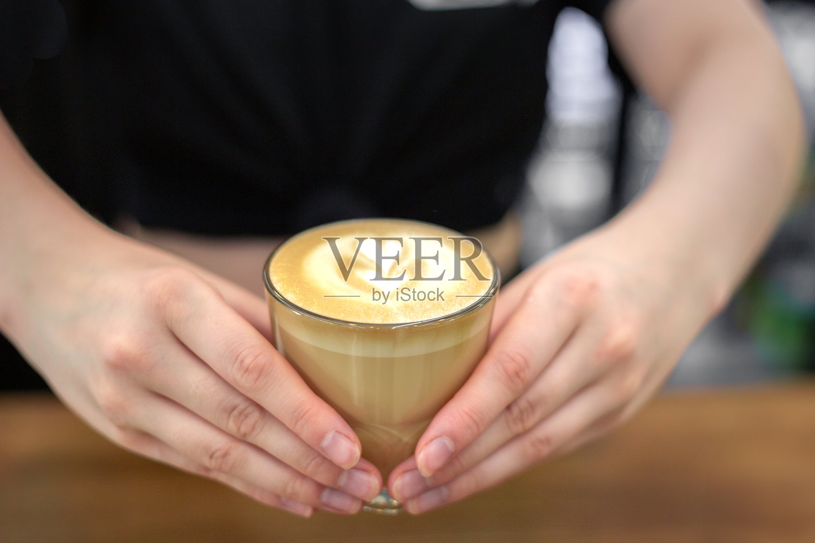 咖啡师双手捧着一杯咖啡。手和咖啡的特写。照片摄影图片