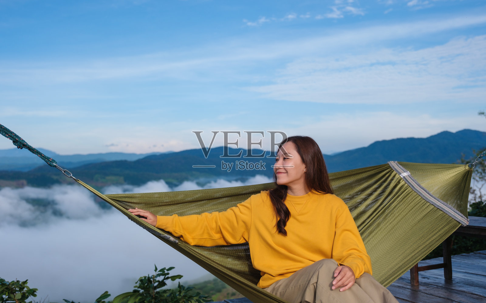 年轻女性坐在吊床上,欣赏山景和雾海。照片摄影图片