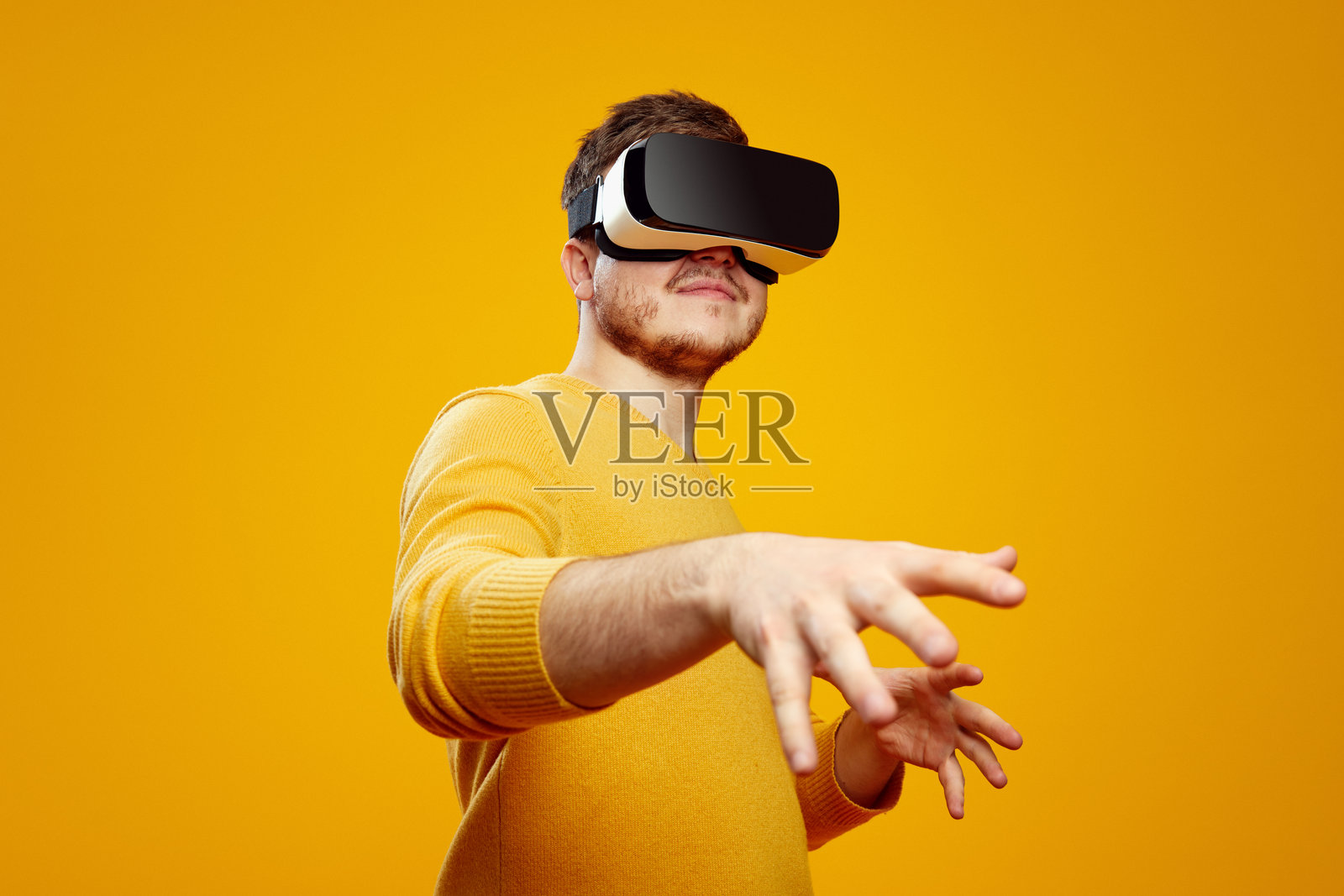 专注的年轻胡子男士戴着虚拟现实头盔,触摸空气照片摄影图片