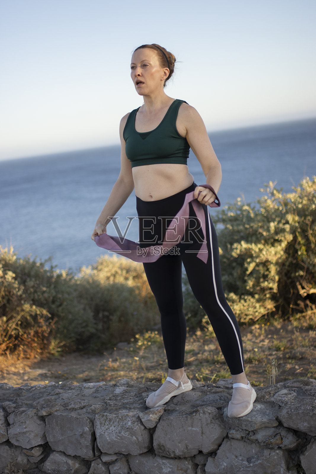 女人在海边日落时用阻力带锻炼照片摄影图片