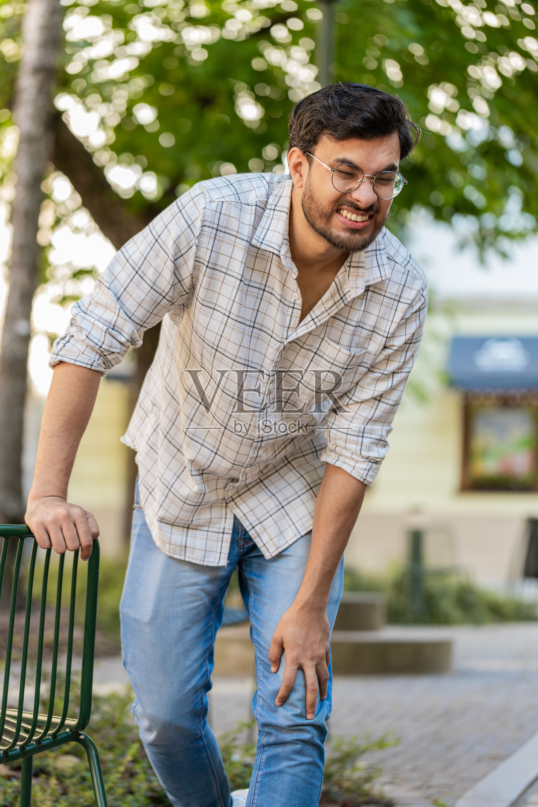 印度年轻男子遭受严重的膝关节疼痛、腿部肌肉痉挛和风湿病的折磨照片摄影图片