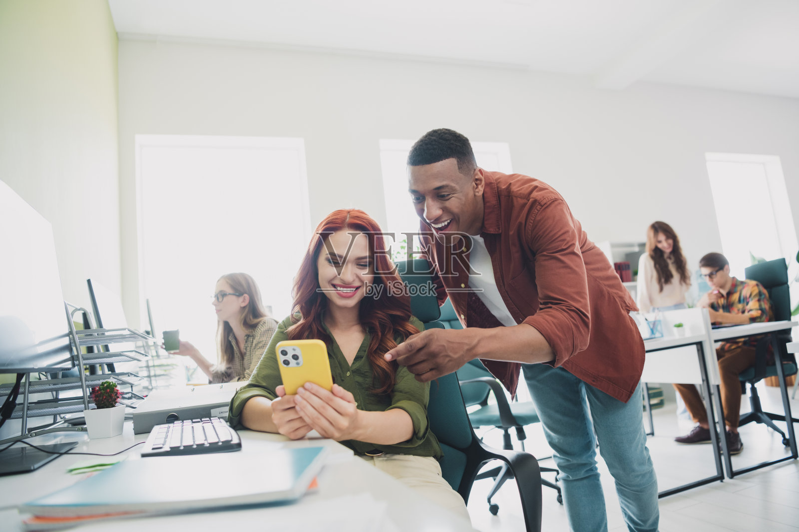 微笑的快乐网页设计师们在室内工作站一起合作,使用现代设备进行交流。照片摄影图片