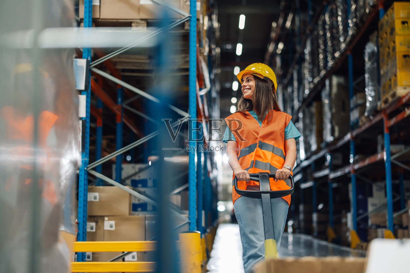 女性仓库工人在配送中心推着托盘车照片摄影图片