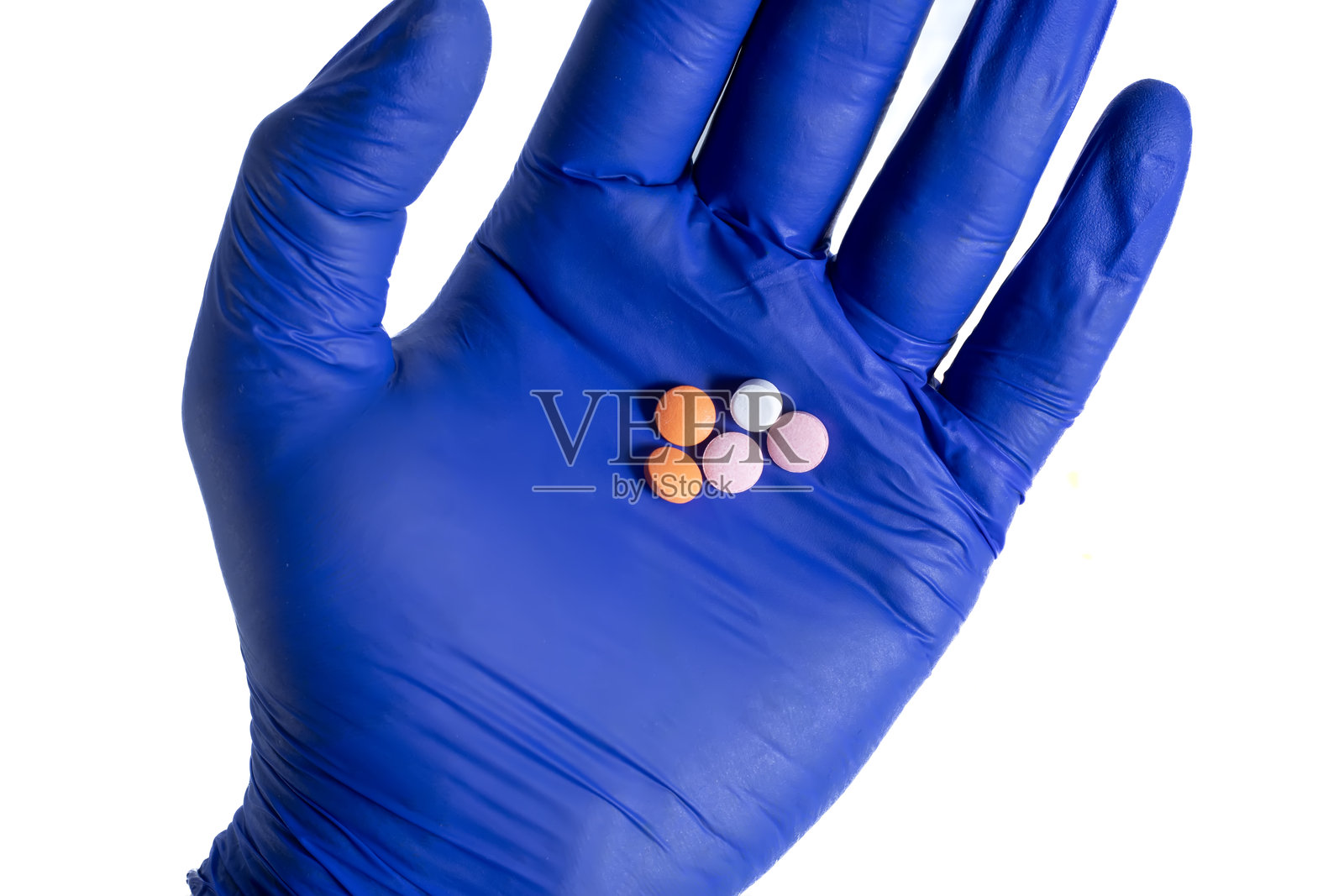 医生戴着蓝色手套,手掌上握着多种颜色的药丸,背景为白色。照片摄影图片