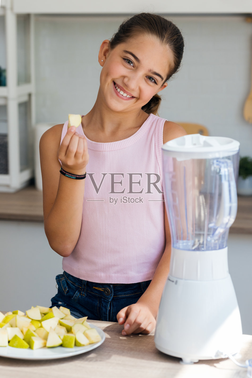 善良的小女孩在家里的厨房用搅拌机制作健康的果汁照片摄影图片