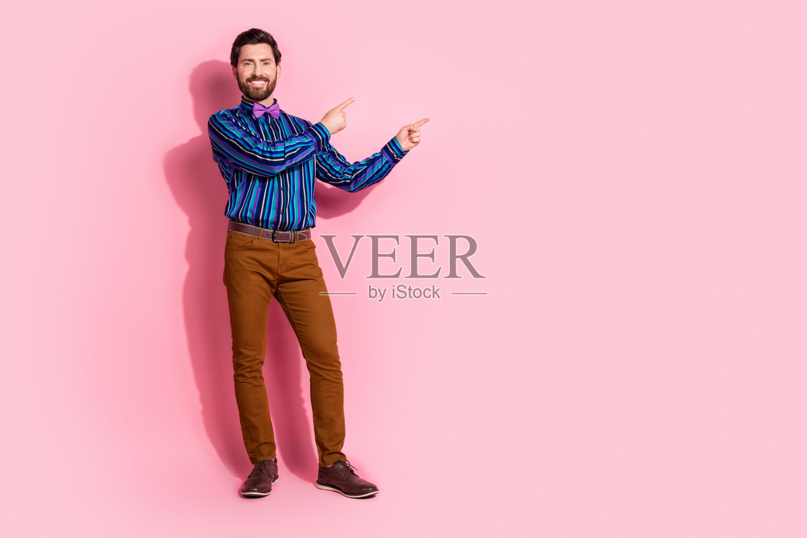 英俊迷人的男士穿着时尚服装,在粉色背景上展示空白空间照片摄影图片