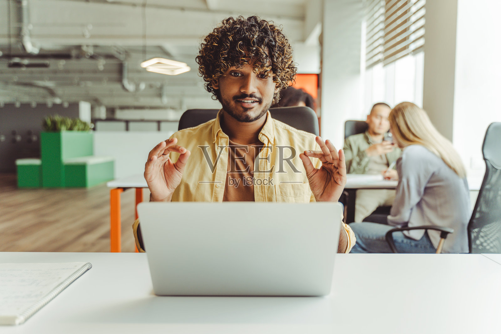 年轻的印度自由职业者在共享办公空间中冥想,旁边有一台笔记本电脑照片摄影图片