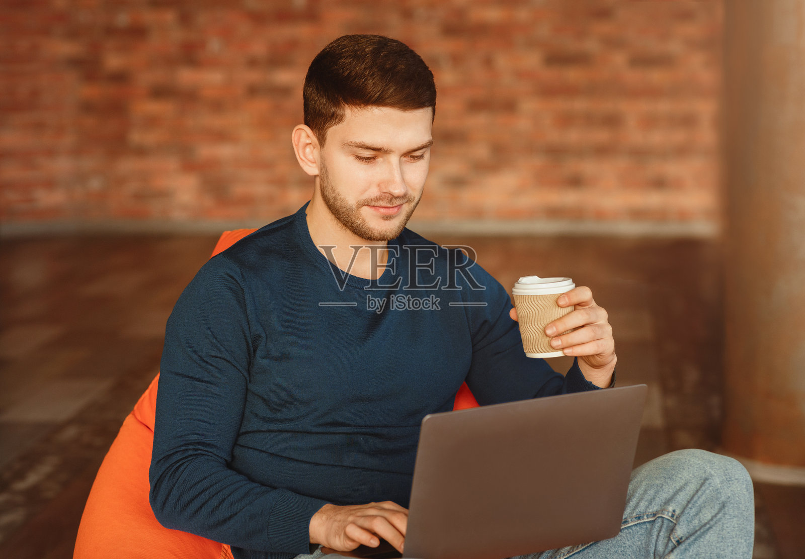 在现代共享办公空间中工作的自由职业者男士坐在笔记本电脑前照片摄影图片