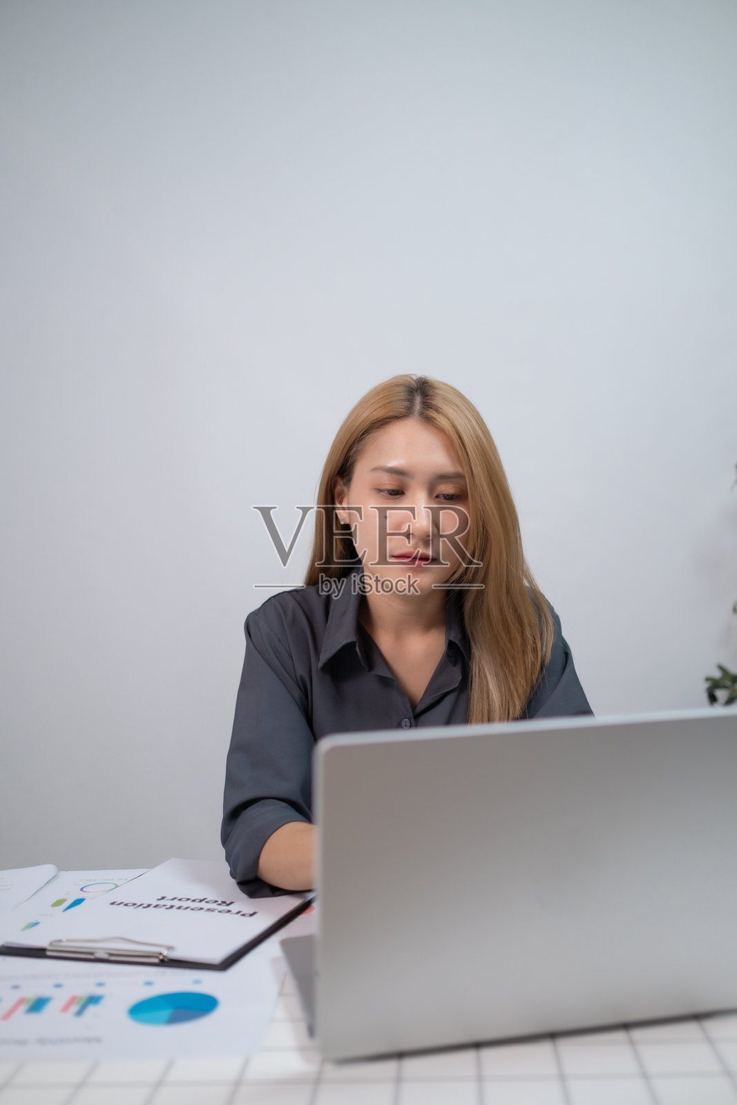 专注的职业女性在家中的客厅使用笔记本电脑,职业女性在办公室使用笔记本电脑阅读财务报告。照片摄影图片