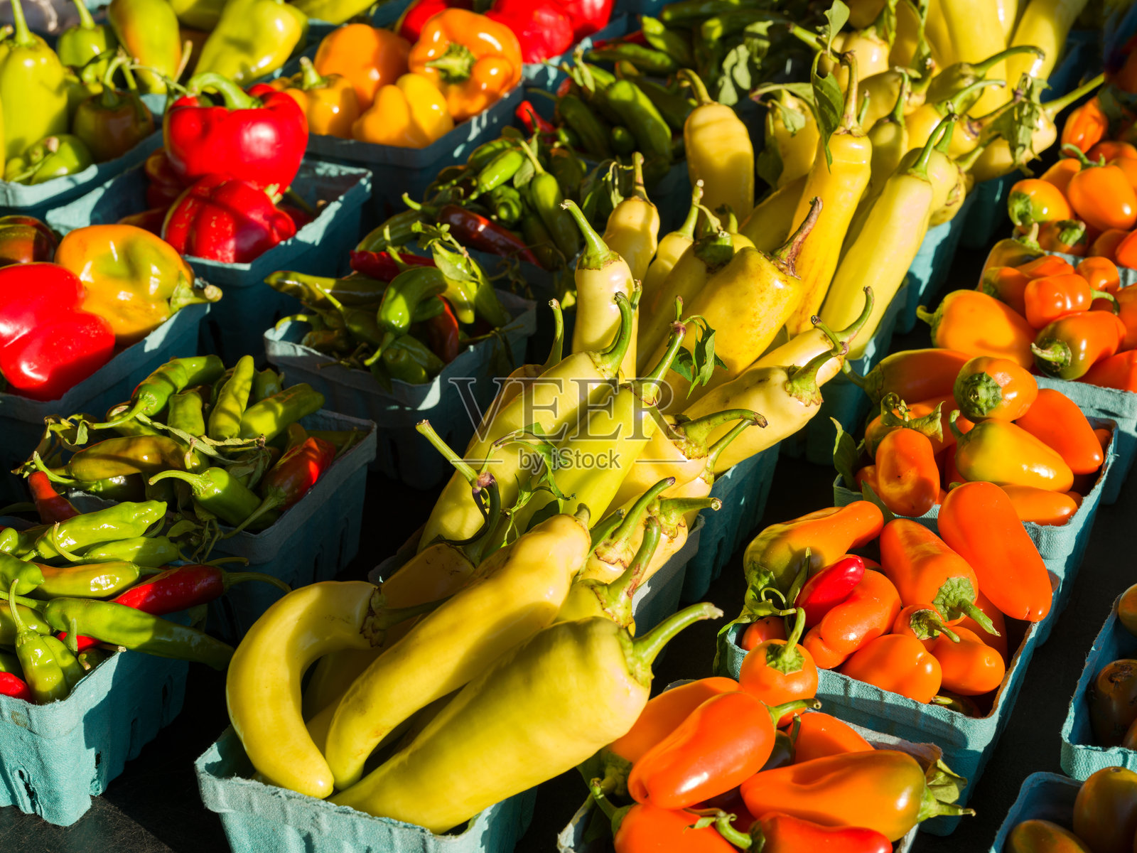清晨的阳光照耀着当地农贸市场上色彩鲜艳的新鲜辣椒。照片摄影图片