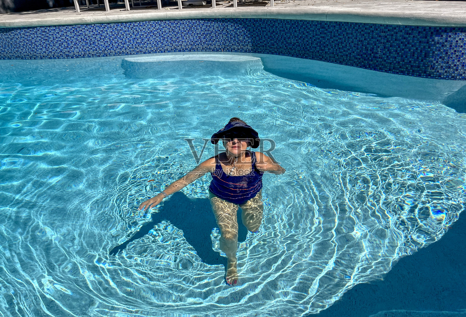 迷人的西班牙裔老年女性在游泳池中照片摄影图片