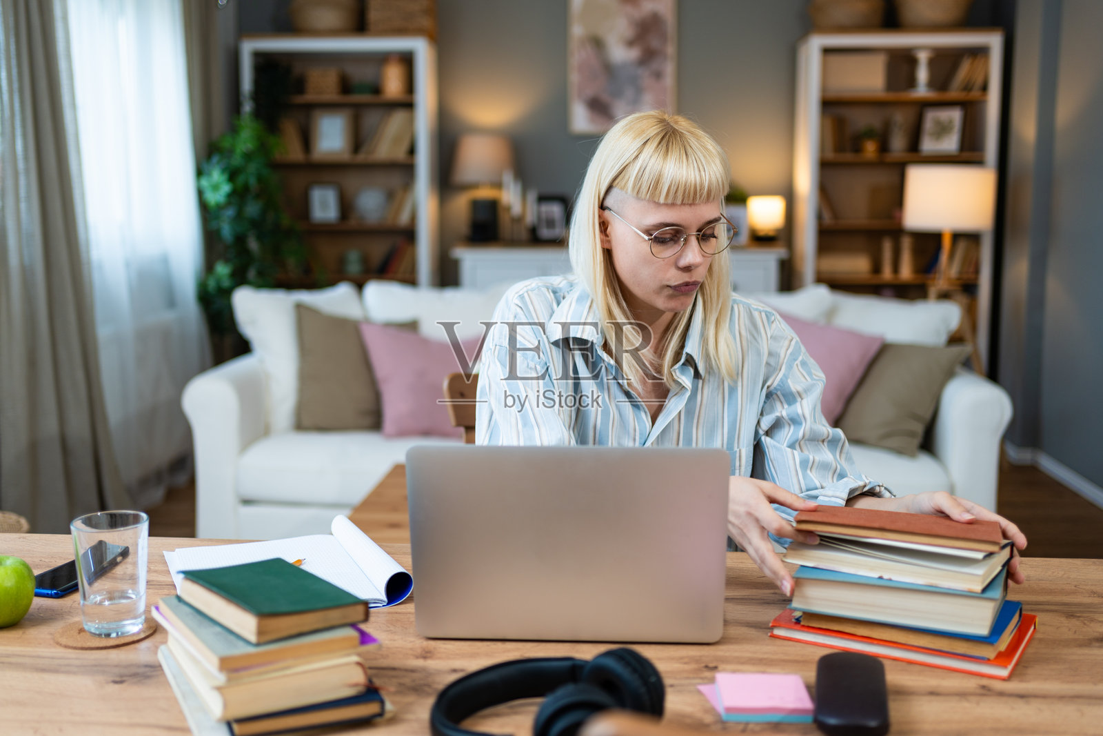 年轻专注且严肃的女性自由职业商业专家在家中办公室使用笔记本电脑工作。金融和经济专业人士正在完成客户的计算工作。照片摄影图片