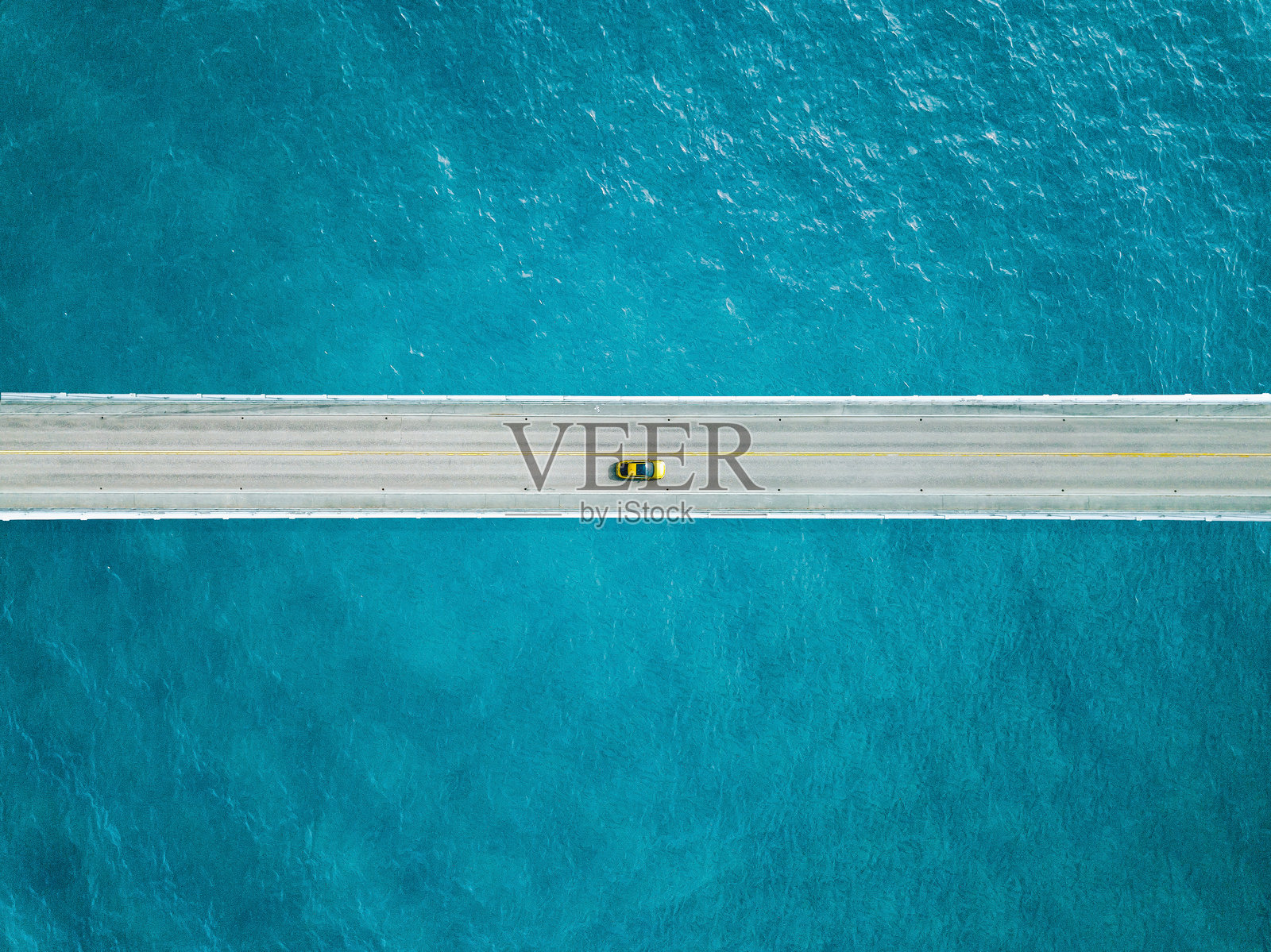 从空中俯瞰蓝色海洋上有一辆黄色汽车的桥梁道路照片摄影图片