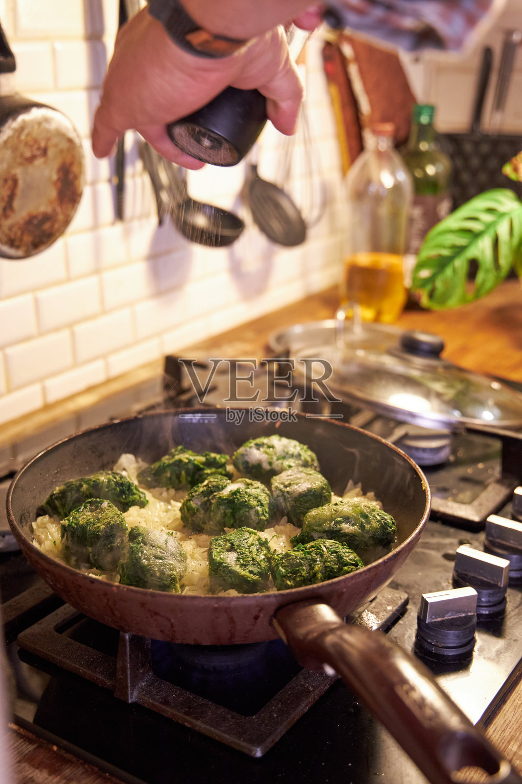 一个男人在炉子上的平底锅里煎炒蔬菜照片摄影图片