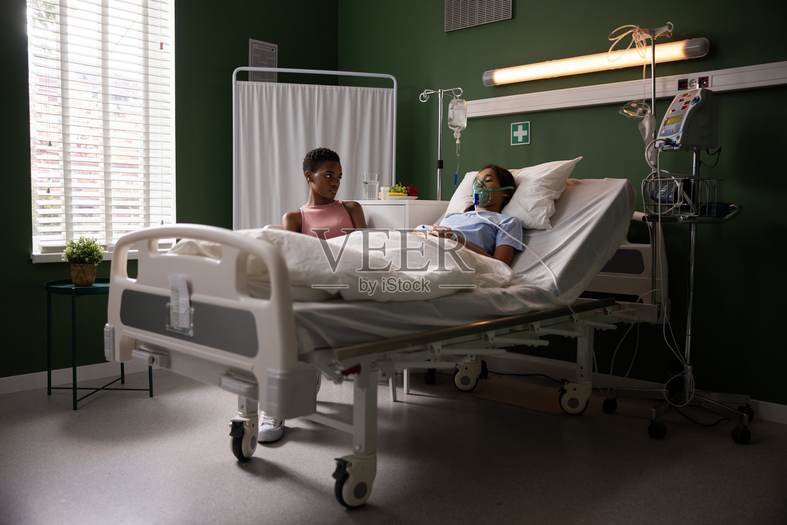 妈妈在医院病房里陪伴着戴着氧气面罩的女儿。照片摄影图片