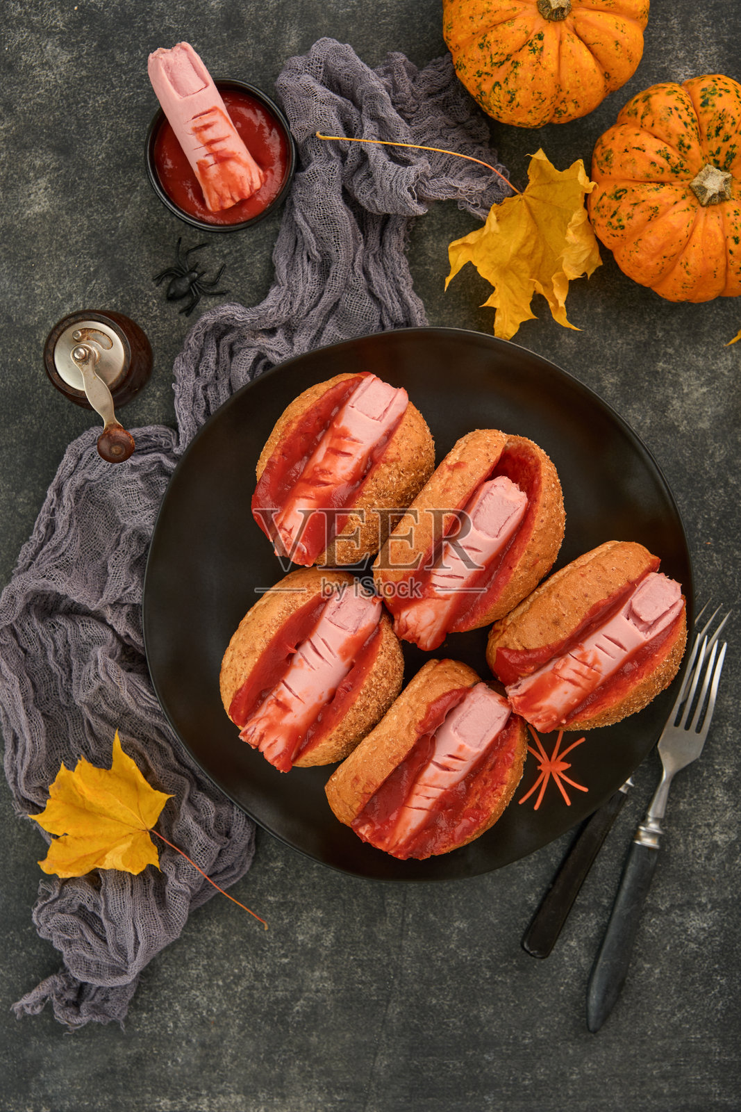 万圣节背景。黑暗的桌子上摆放着自制热狗和血淋淋的手指,适合万圣节的主题食品庆祝派对。留白空间。照片摄影图片