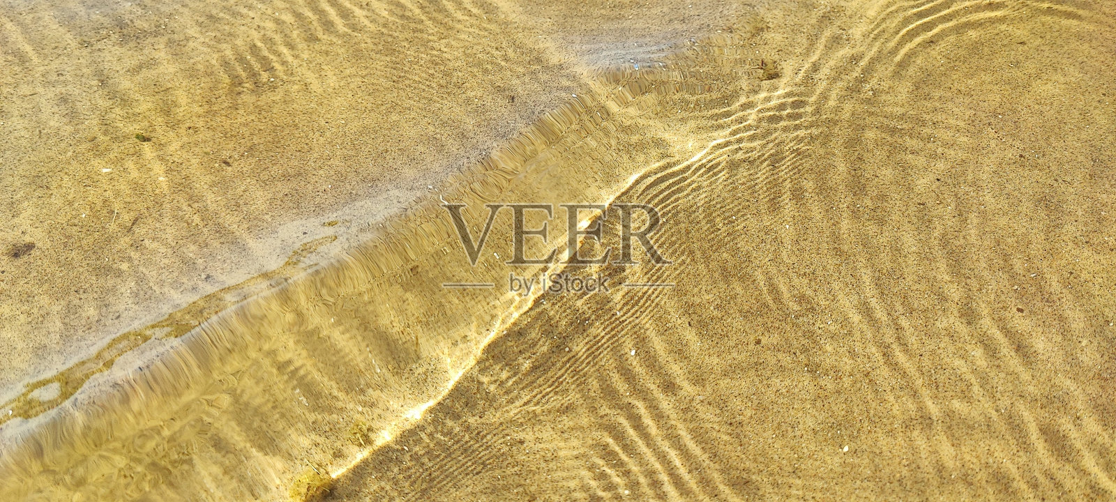 水面上小波浪,下面是沙子。照片摄影图片