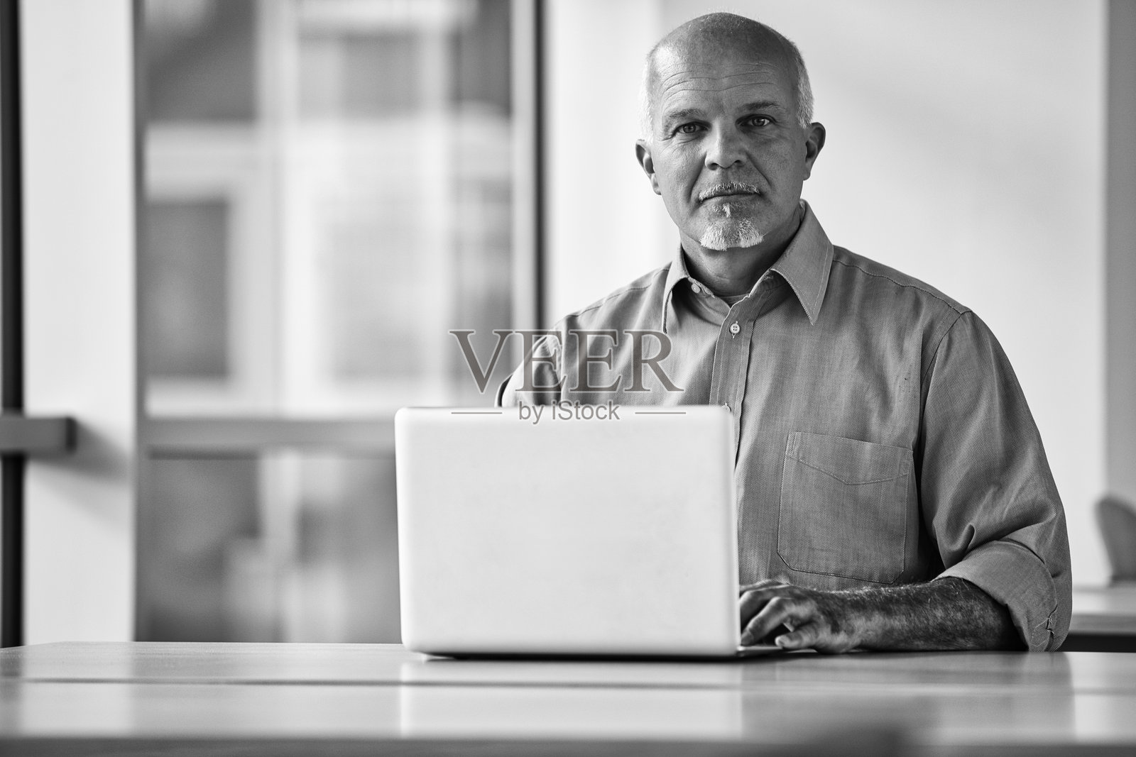 成熟的商人在现代办公室使用笔记本电脑工作照片摄影图片