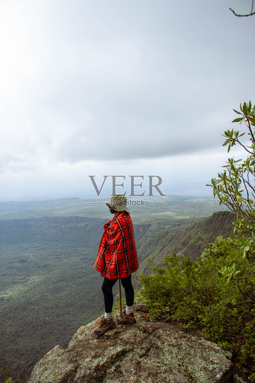 一名登山者站在山顶,眺望火山口。照片摄影图片