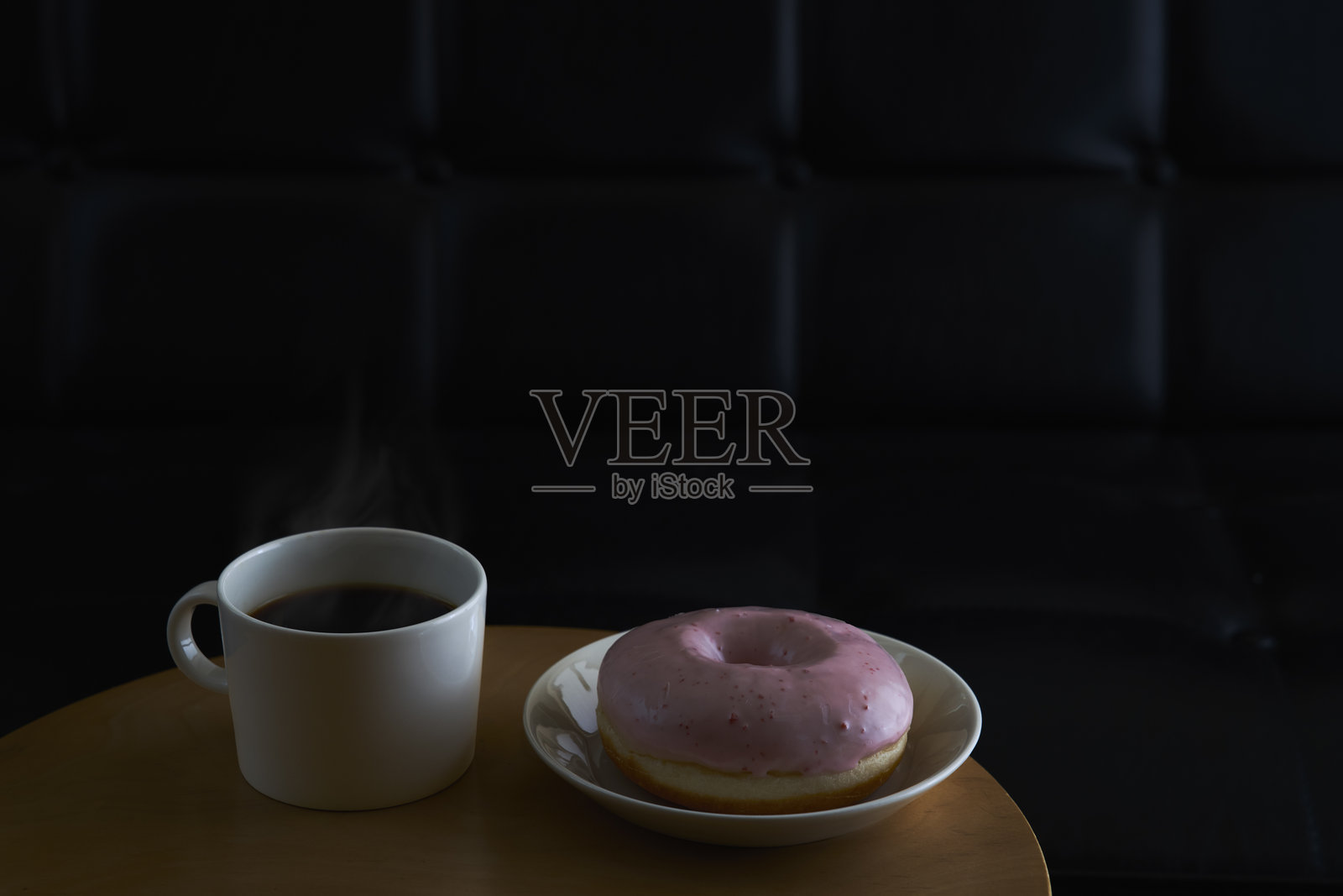 在沙发上放松,手里捧着一杯热咖啡和一个甜甜圈照片摄影图片